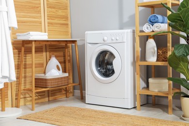 Photo of Washing machine, towels and detergents in laundry room