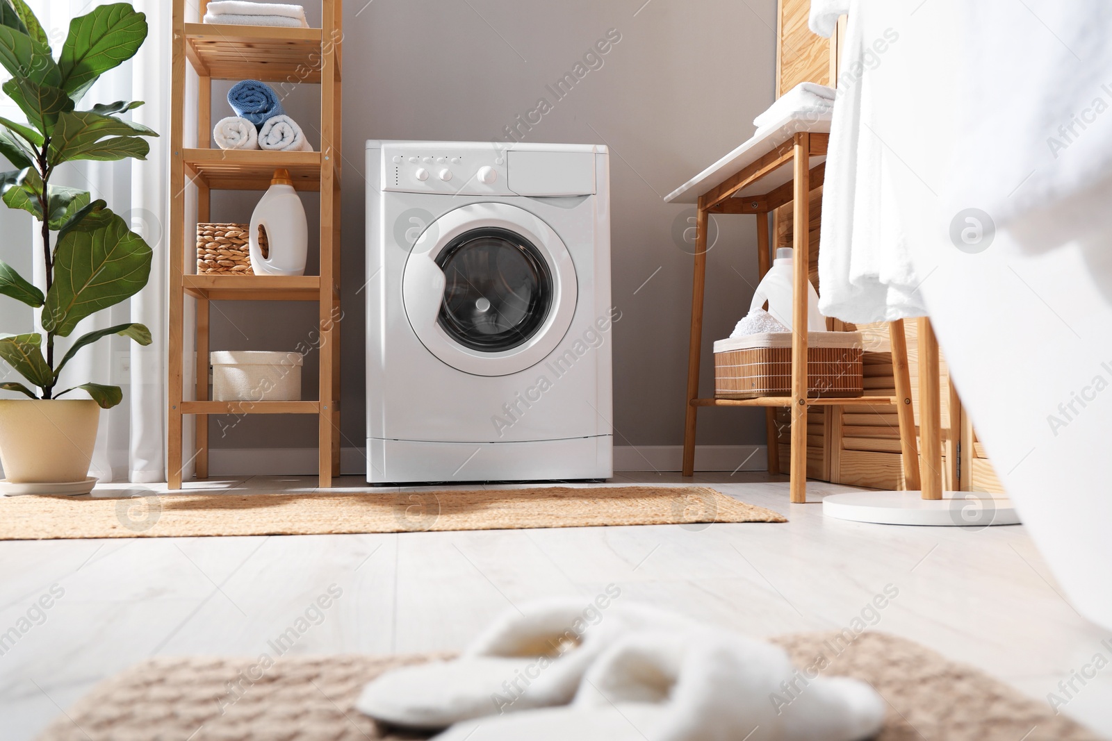 Photo of Washing machine, towels and detergents in laundry room