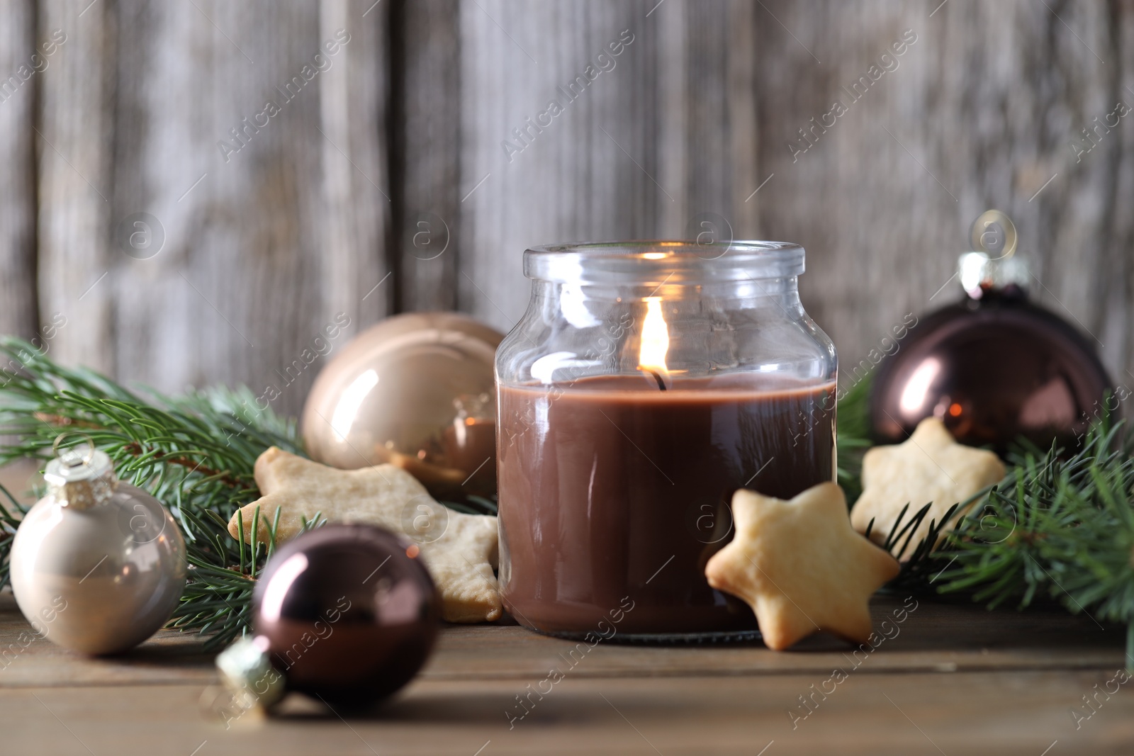 Photo of Burning candle, baubles, cookies and fir branches on wooden table. Christmas atmosphere