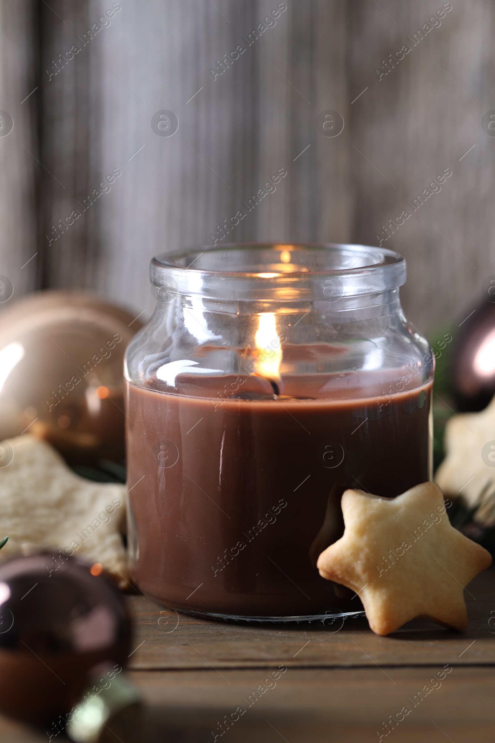 Photo of Burning candle, baubles and cookies on wooden table, closeup. Christmas atmosphere