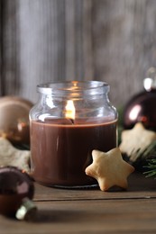 Photo of Burning candle, baubles and cookies on wooden table, closeup. Christmas atmosphere