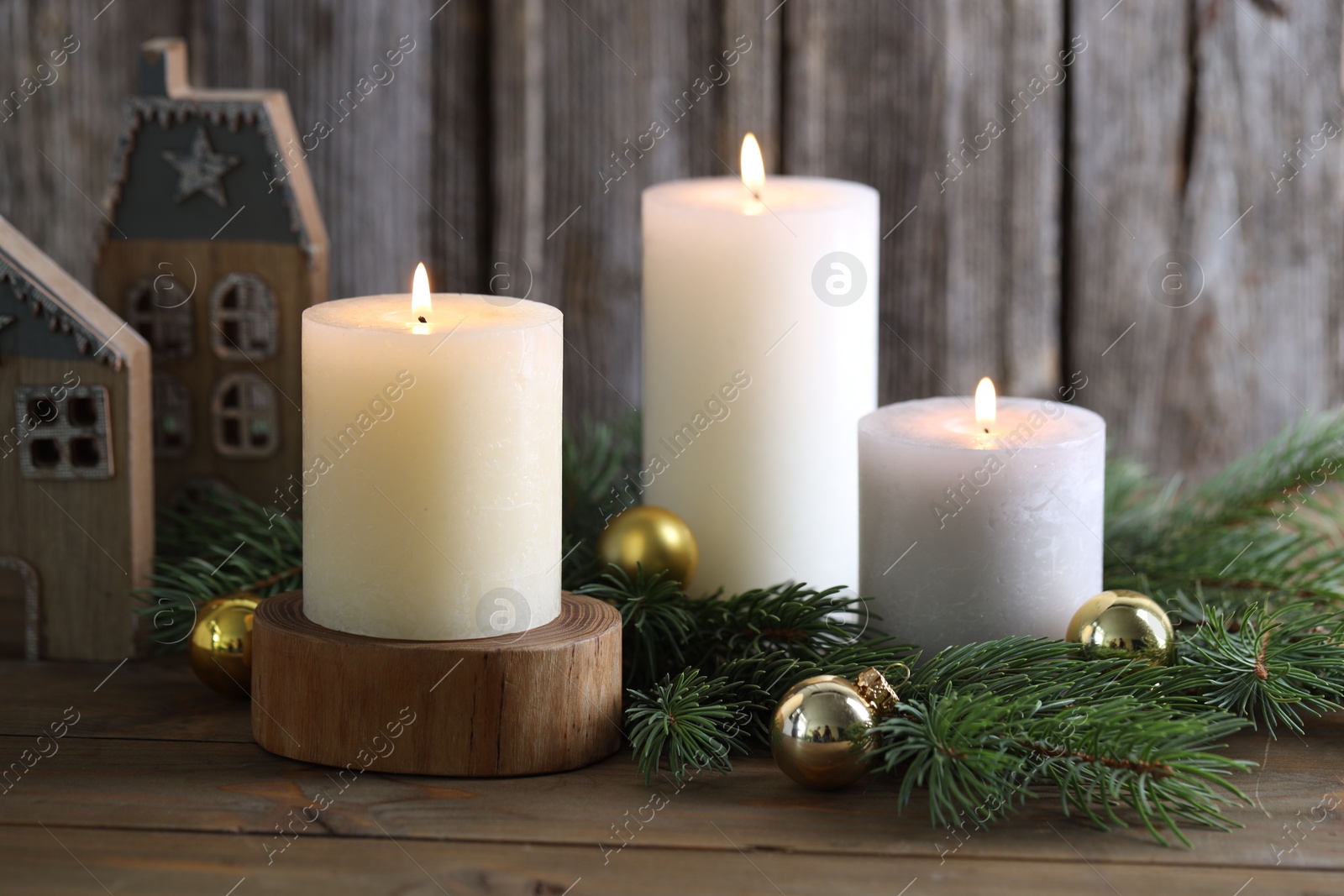 Photo of Burning candles, baubles, fir branches and other Christmas decor on wooden table