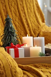 Photo of Tray with burning candles and Christmas decor on armchair