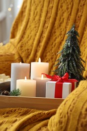 Photo of Tray with burning candles and Christmas decor on armchair