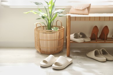 Many pairs of slippers and other shoes in entryway at home