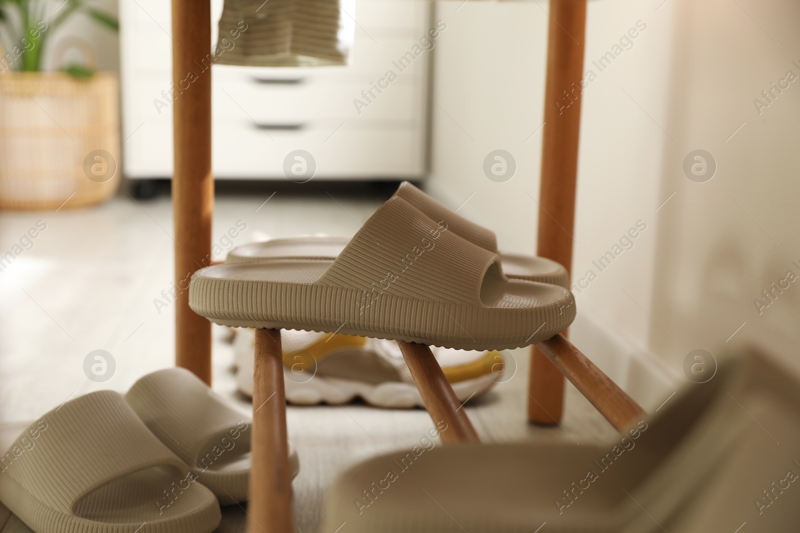 Photo of Pair of slippers on shoe rack at home