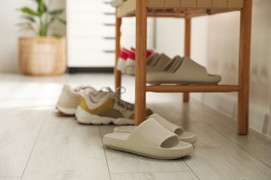 Many pairs of slippers and other shoes in entryway at home