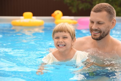 Happy daughter and her father having fun in swimming pool. Space for text