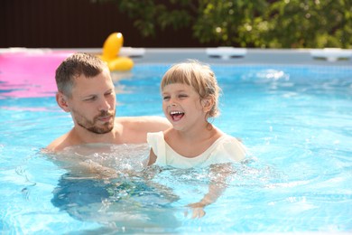 Photo of Happy daughter and her father having fun in swimming pool