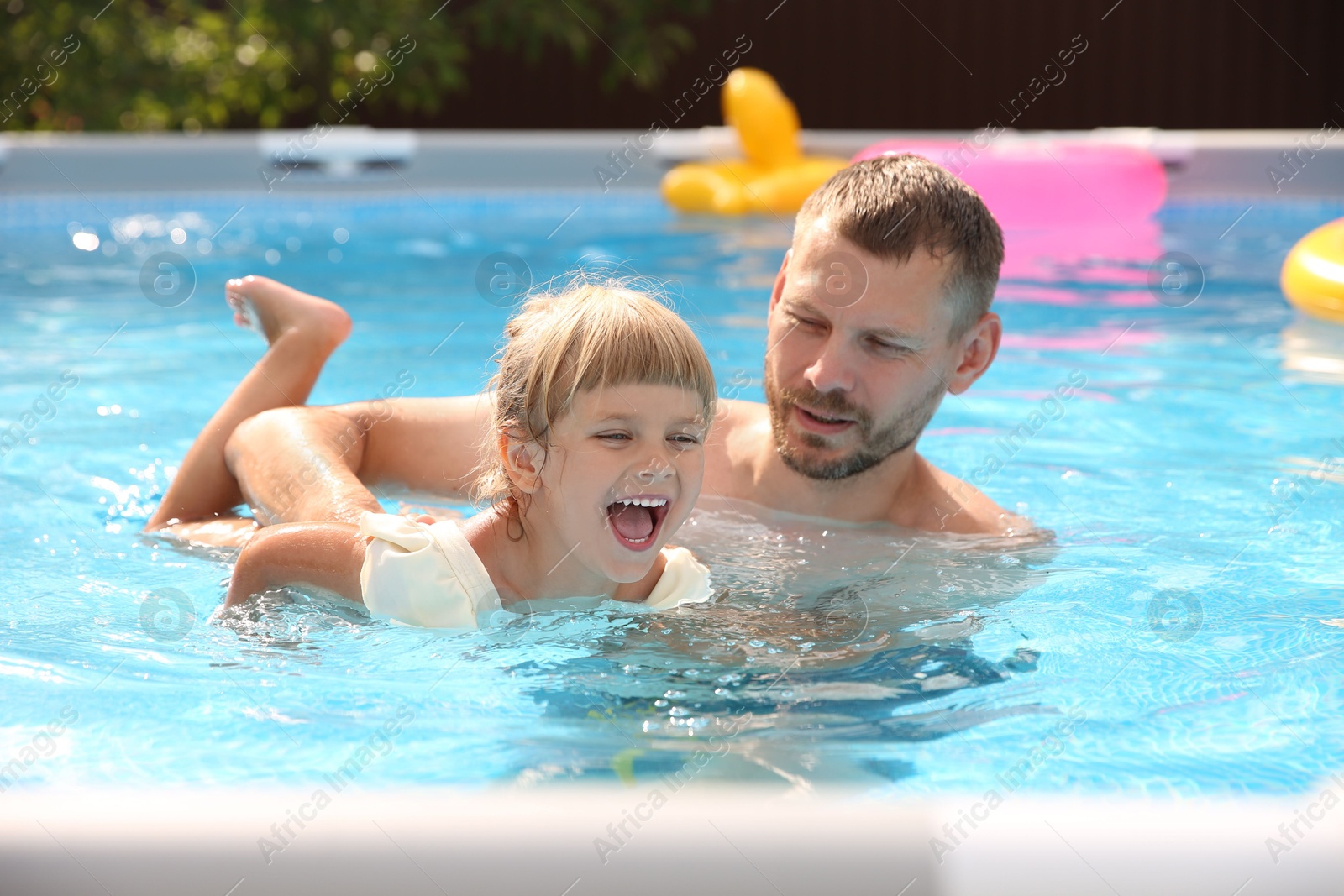 Photo of Happy daughter and her father having fun in swimming pool