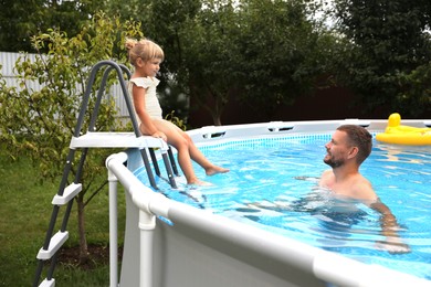 Photo of Little daughter and her father resting in swimming pool