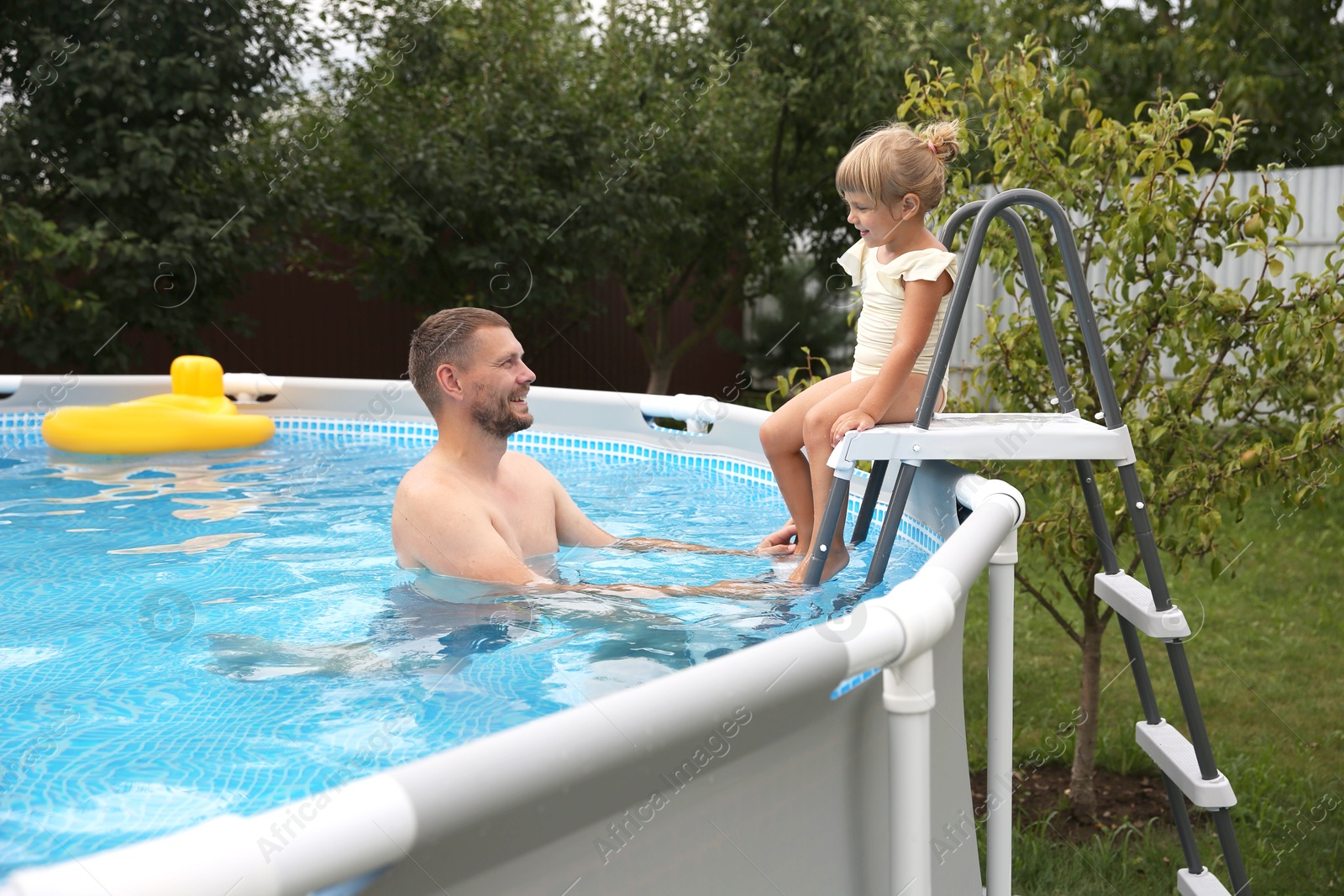 Photo of Little daughter and her father resting in swimming pool