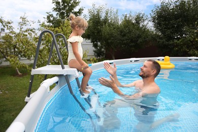 Photo of Little daughter and her father resting in swimming pool