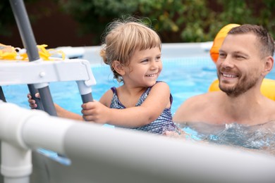 Photo of Happy daughter and her father near ladder in swimming pool