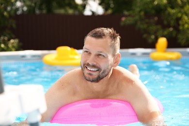 Photo of Happy man swimming with inflatable ring outdoors