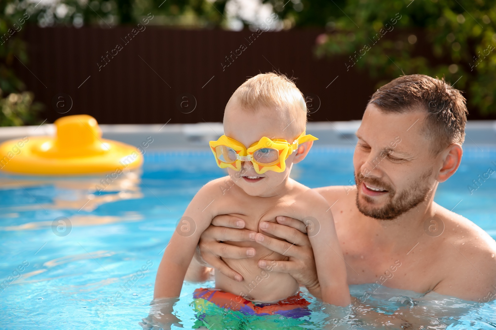 Photo of Happy father having fun with his son in swimming pool