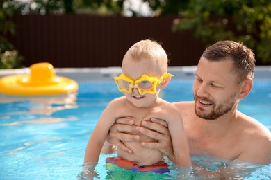 Photo of Happy father having fun with his son in swimming pool