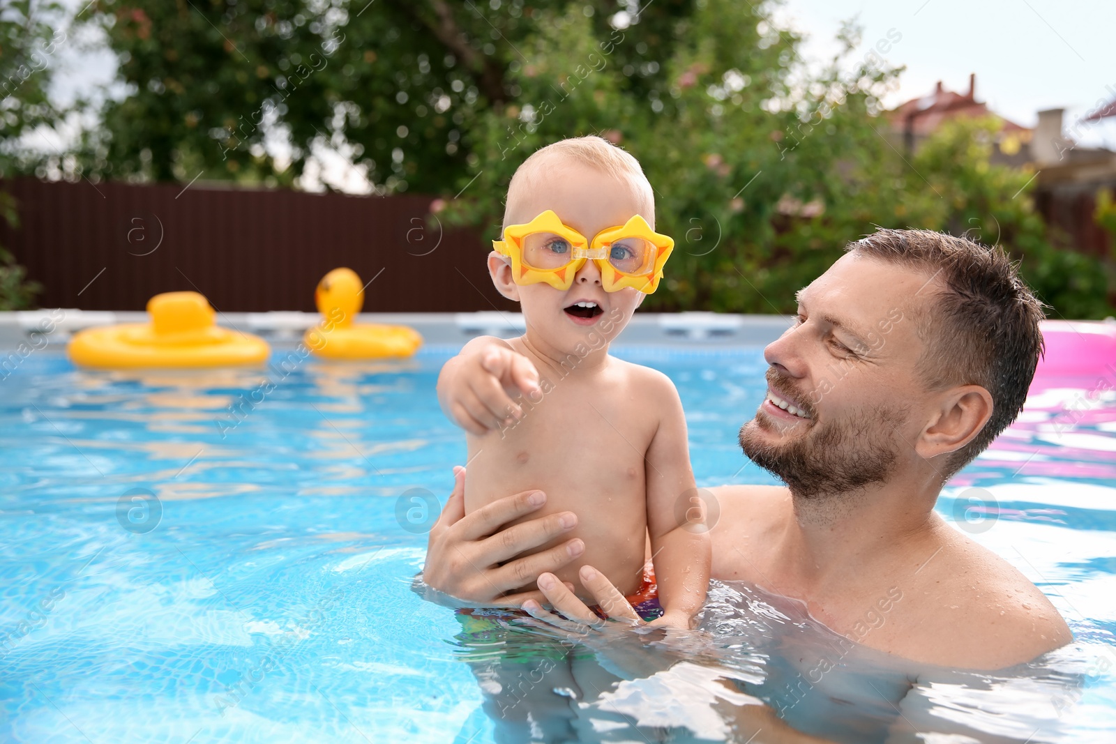 Photo of Happy father having fun with his son in swimming pool