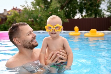 Photo of Happy father having fun with his son in swimming pool