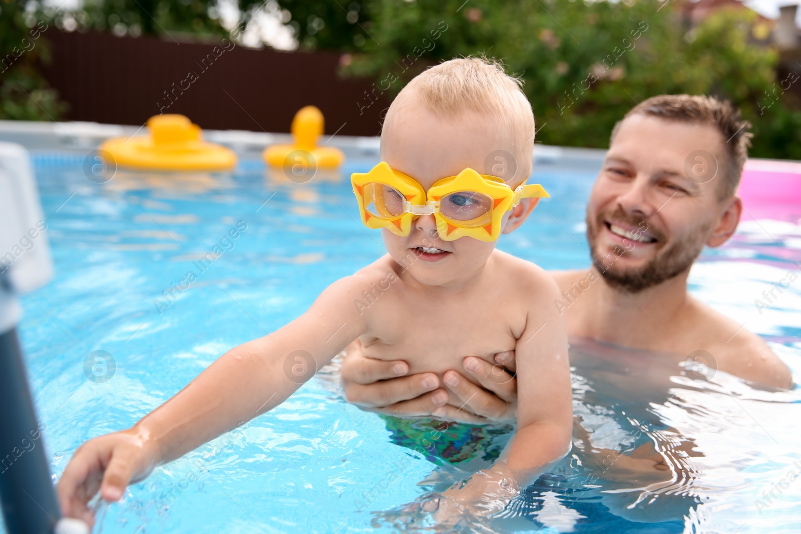 Photo of Happy father having fun with his son in swimming pool