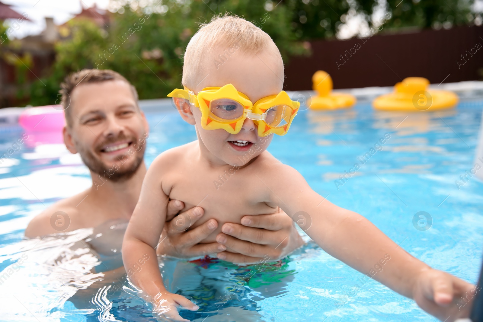 Photo of Happy father having fun with his son in swimming pool