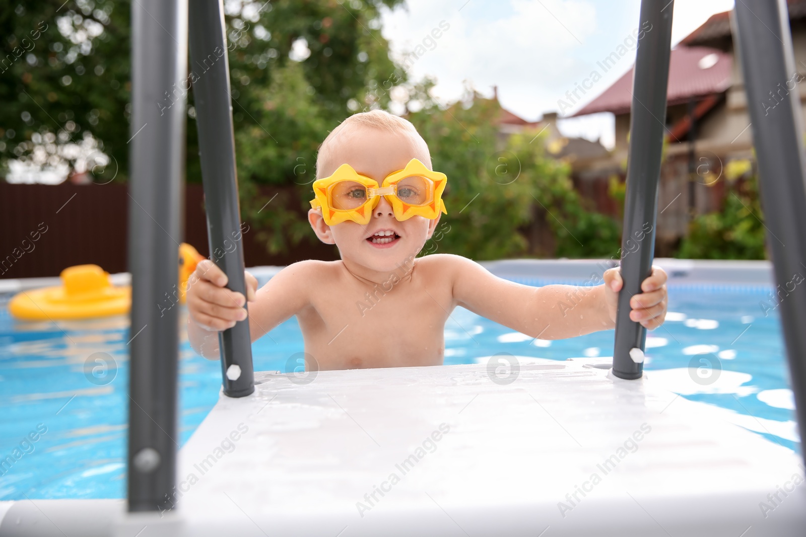 Photo of Little boy getting out of swimming pool by ladder outdoors