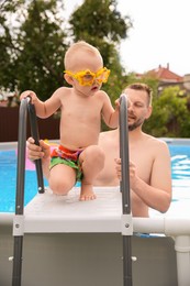 Photo of Father helping to his son getting out of swimming pool outdoors