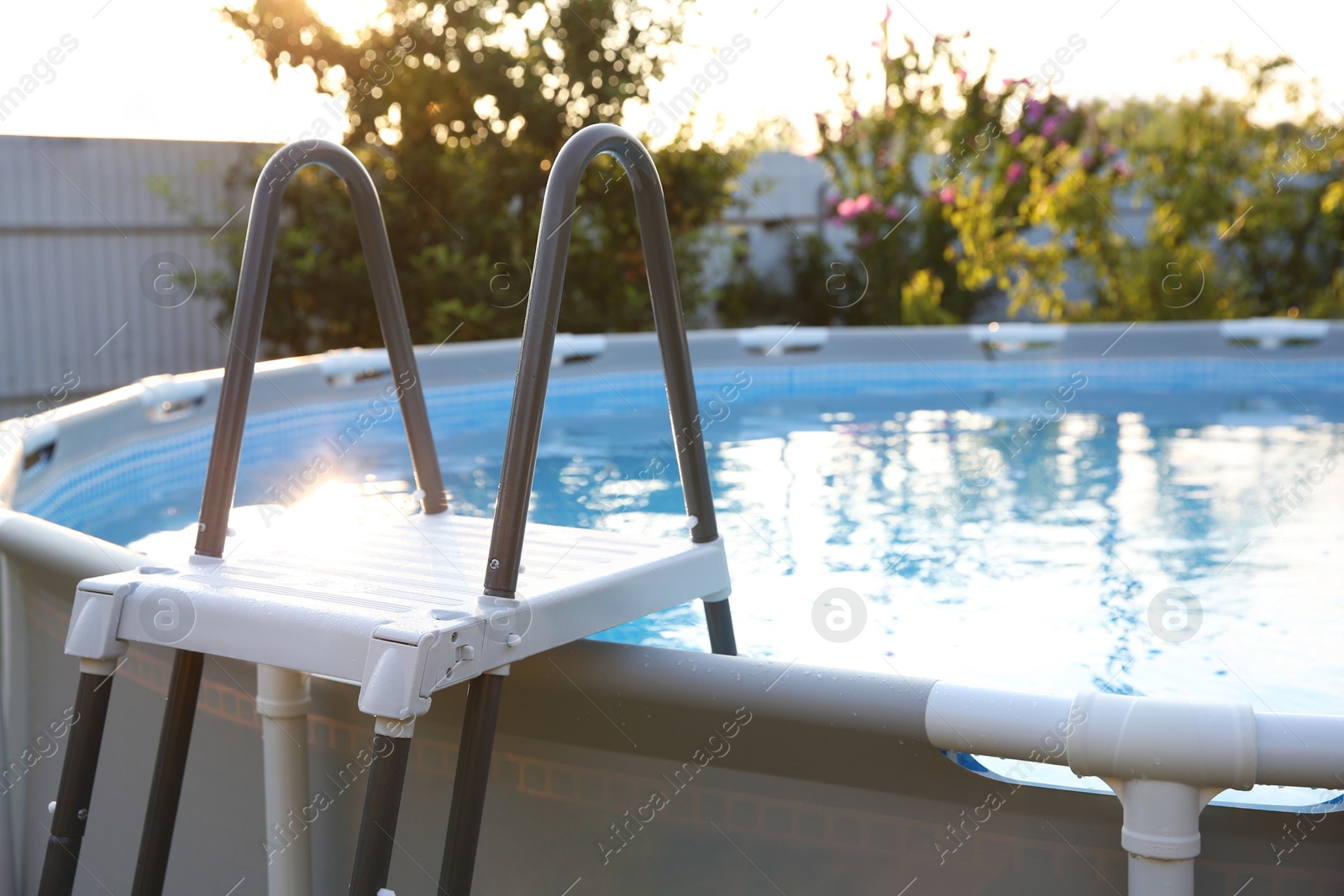 Photo of Above ground swimming pool with ladder outdoors on sunny day