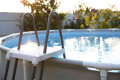 Photo of Above ground swimming pool with ladder outdoors on sunny day