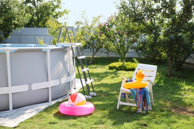 Above ground swimming pool, folding chair, towel, inflatable rings and ball in backyard