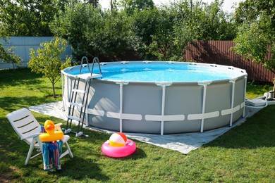 Photo of Above ground swimming pool, folding chair, towel, inflatable rings and ball in backyard