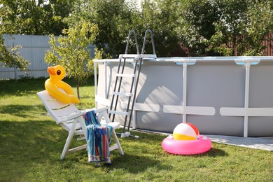 Photo of Above ground swimming pool, folding chair, towel, inflatable rings and ball in backyard