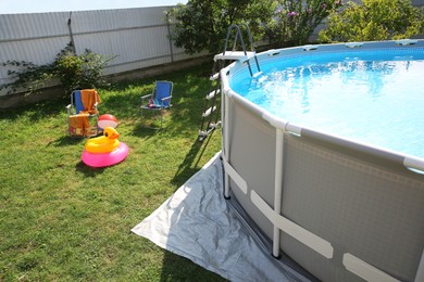 Photo of Above ground swimming pool, folding chairs, towel, inflatable rings and ball in backyard