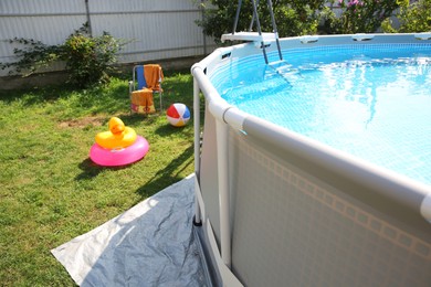 Photo of Above ground swimming pool, folding chairs, towel, inflatable rings and ball in backyard