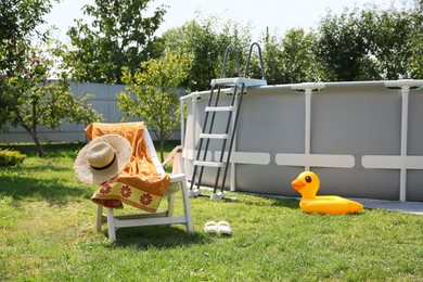 Above ground swimming pool, folding chair, towel, inflatable ring and hat in backyard