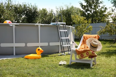 Photo of Above ground swimming pool, folding chair, towel, inflatable ring and hat in backyard