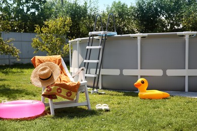 Photo of Above ground swimming pool, folding chair, towel, inflatable rings and hat in backyard