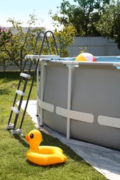 Photo of Above ground swimming pool, inflatable ring and ball outdoors on sunny day