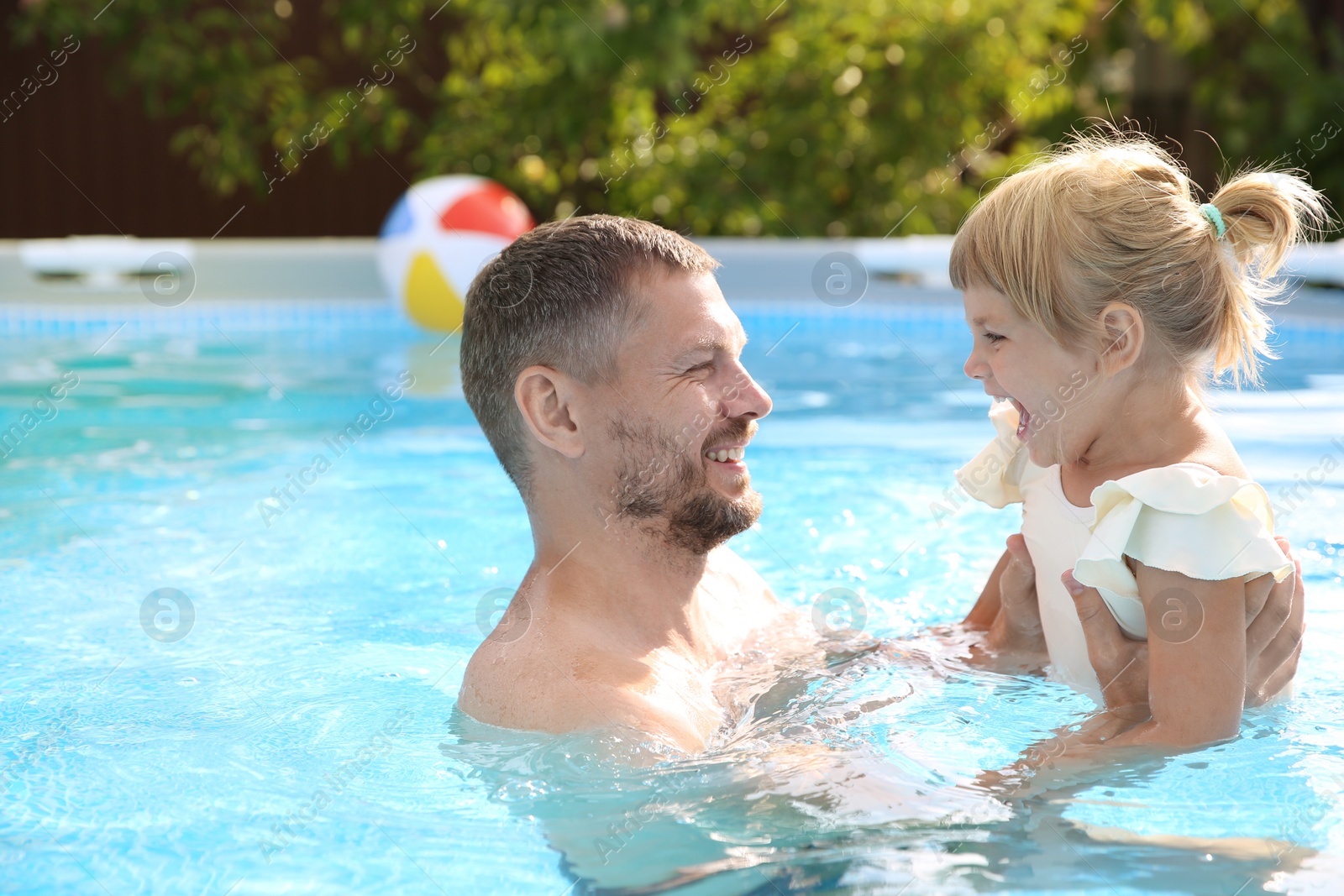 Photo of Happy father having fun with his daughter in swimming pool