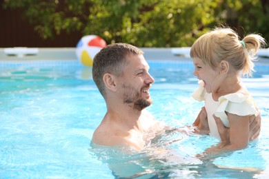 Happy father having fun with his daughter in swimming pool