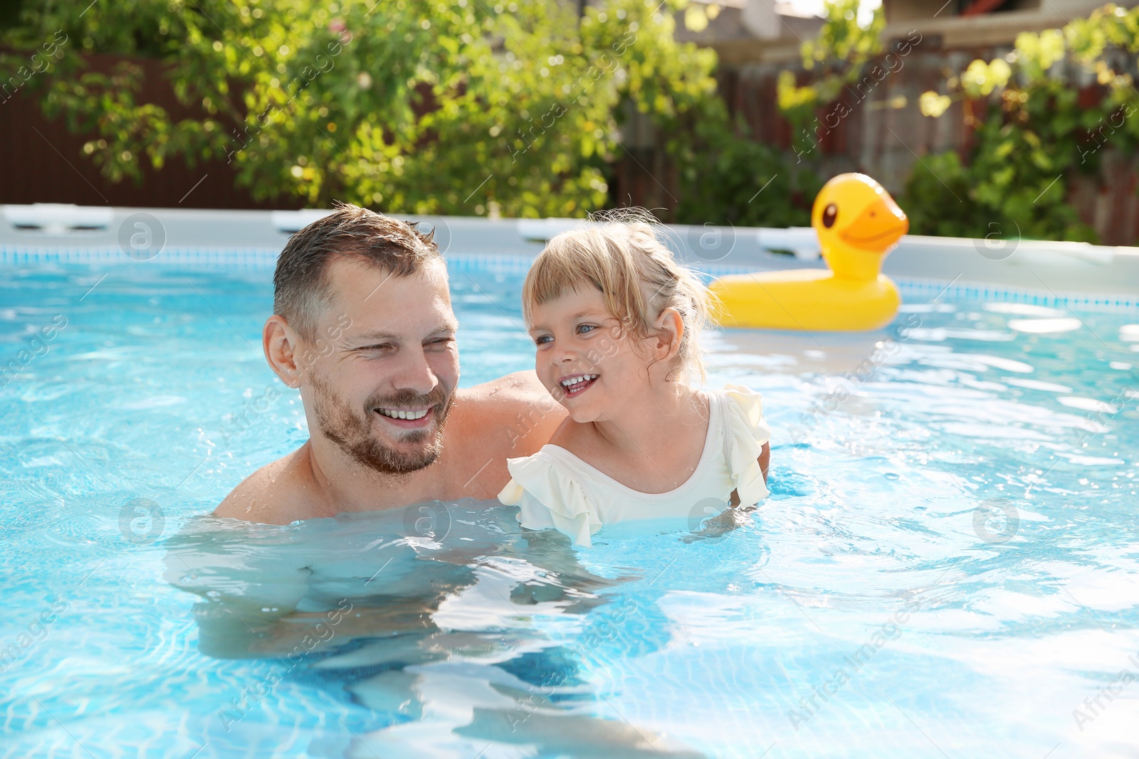 Photo of Happy father having fun with his daughter in swimming pool