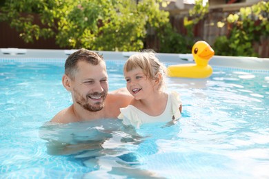 Photo of Happy father having fun with his daughter in swimming pool