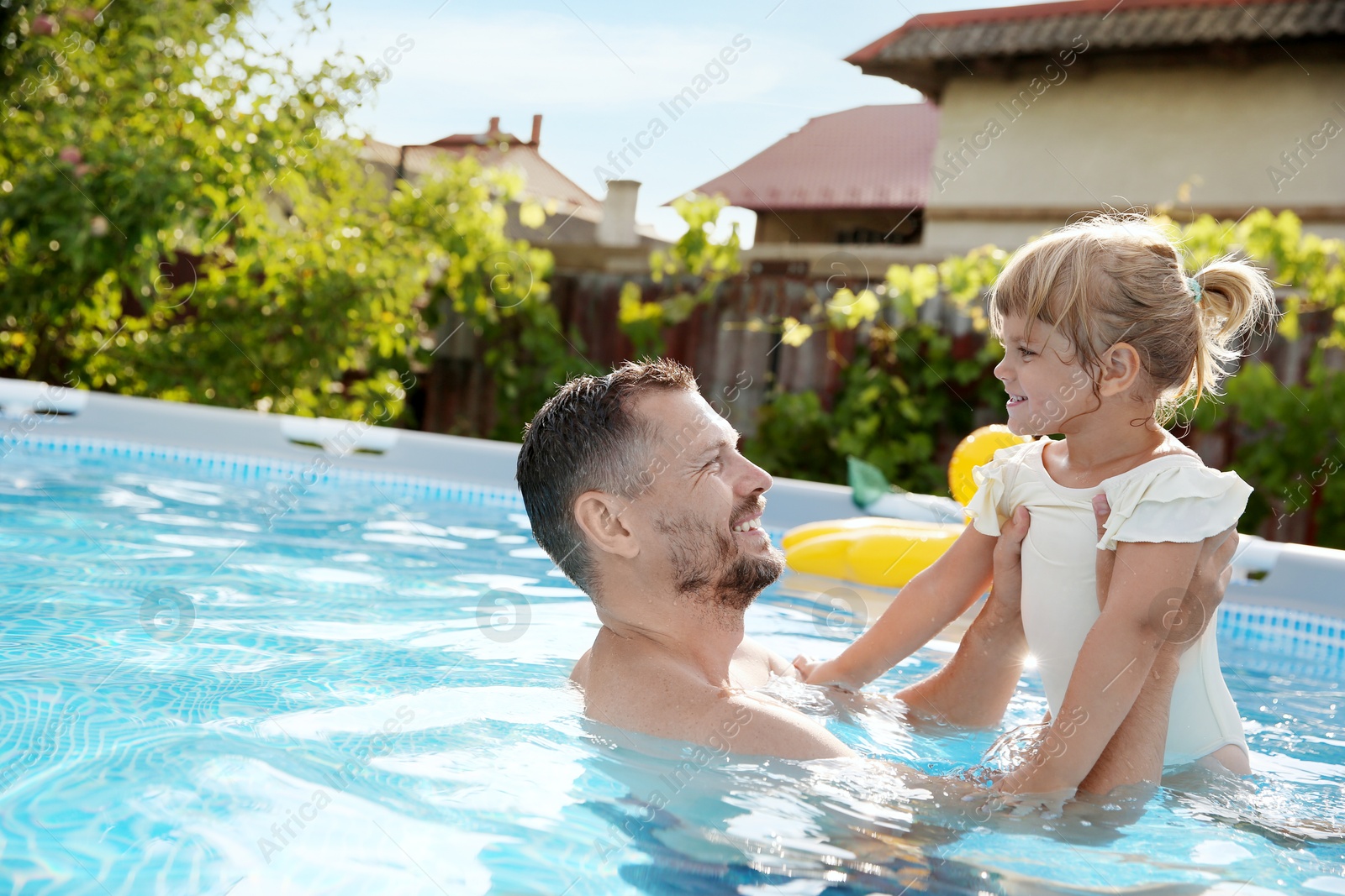 Photo of Happy father having fun with his daughter in swimming pool, space for text