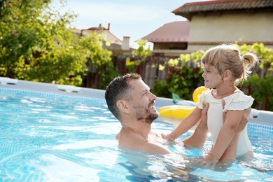 Happy father having fun with his daughter in swimming pool, space for text