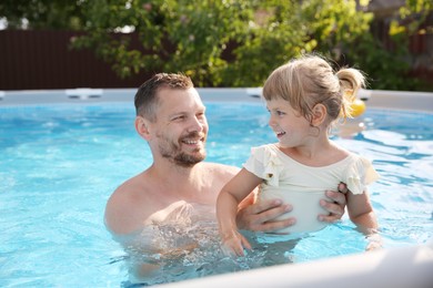 Photo of Happy father having fun with his daughter in swimming pool