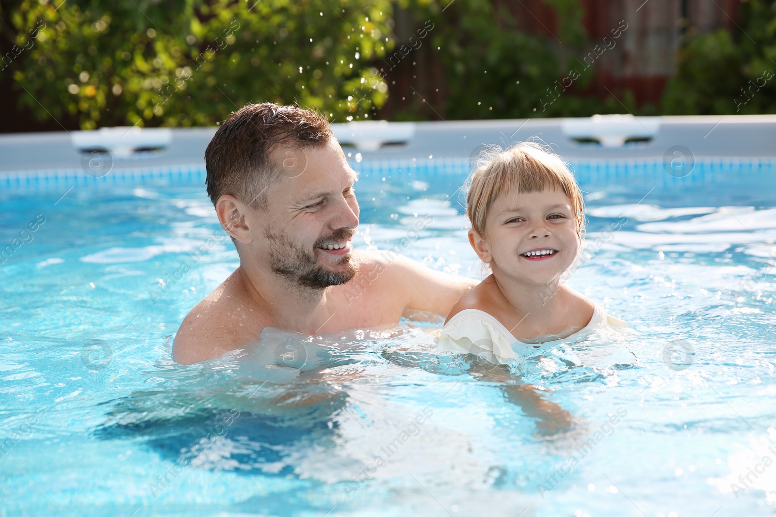 Photo of Happy father having fun with his daughter in swimming pool