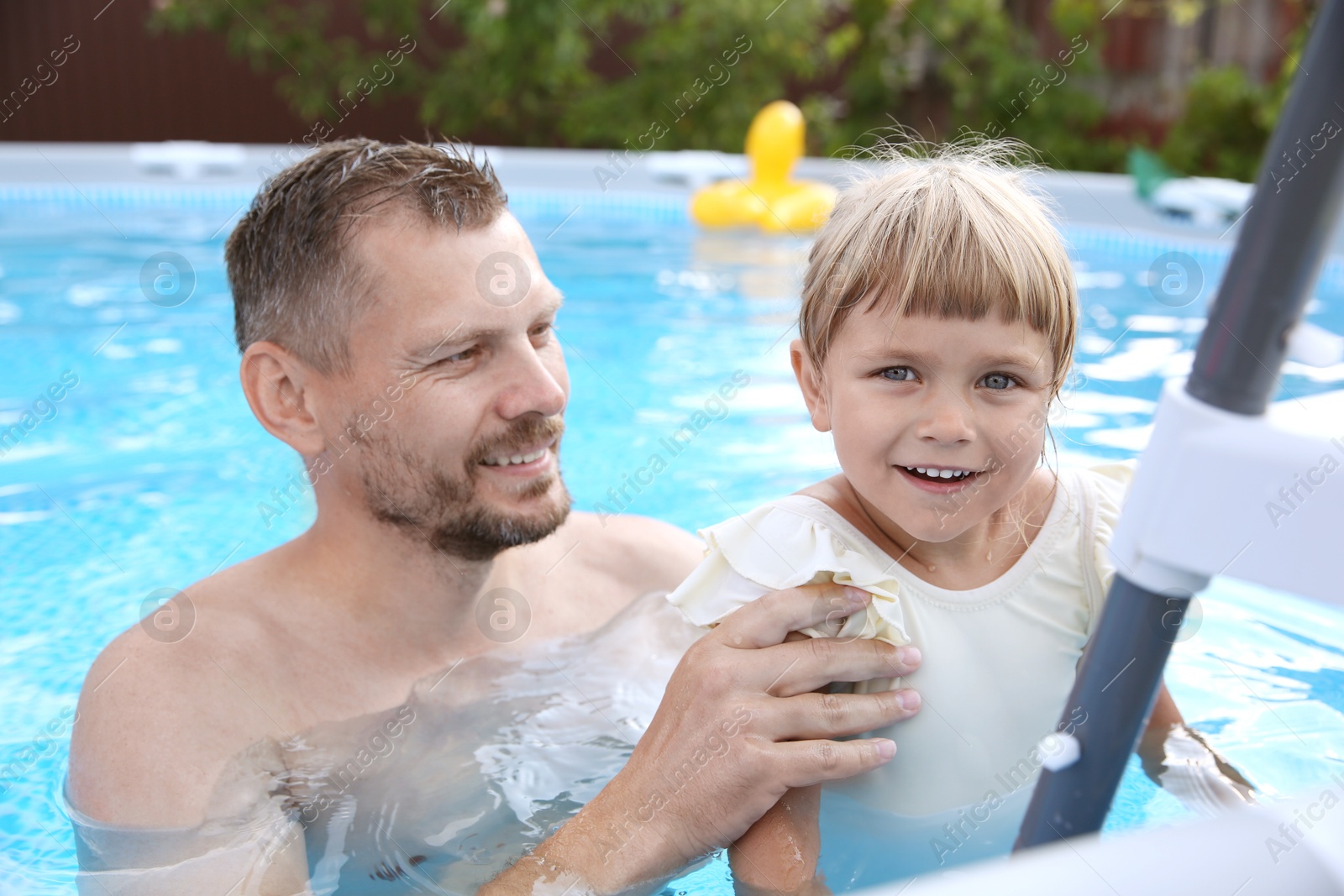 Photo of Happy father and his daughter near ladder in swimming pool