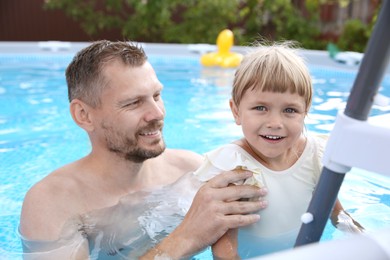 Photo of Happy father and his daughter near ladder in swimming pool