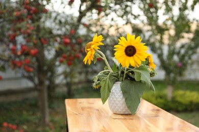 Photo of Vase with sunflowers on wooden table in garden