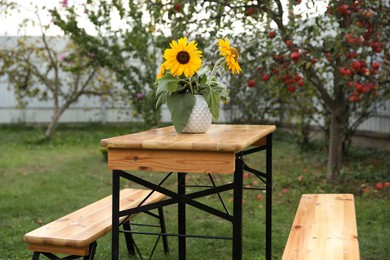 Photo of Vase with sunflowers on wooden table in garden